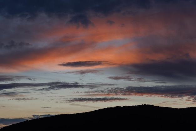 puesta de sol, cielo azul anaranjado y montaña oscura
