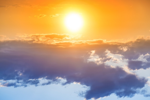 Puesta de sol en el cielo naranja con gran sol y nube azul