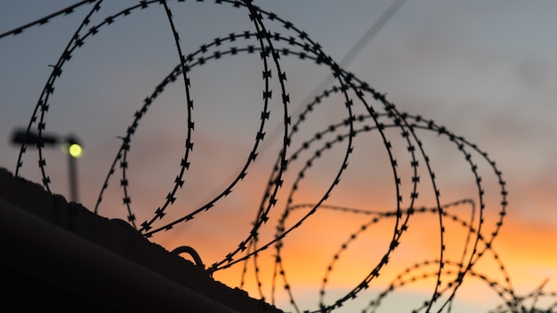 Puesta de sol detrás del alambre de púas a lo largo de la frontera. Sochi, Rusia.