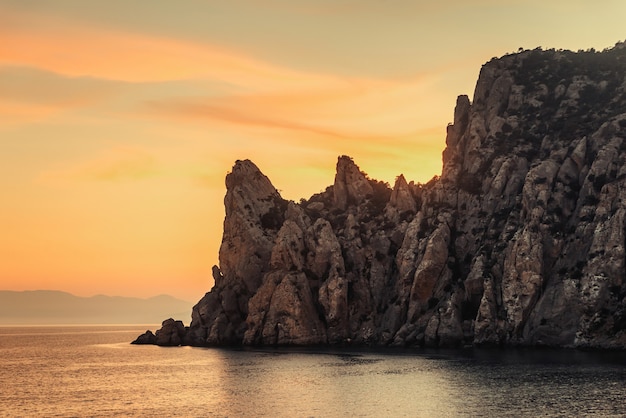 Puesta de sol dorada en la costa rocosa del mar