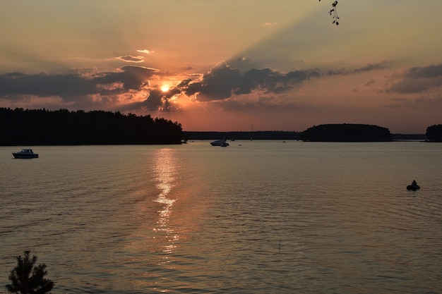 Puesta de sol en el embalse, puesta de sol en el lago, silueta del pescador en el fondo del atardecer