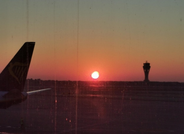 Foto una puesta de sol es visible a través de una ventana en un aeropuerto.