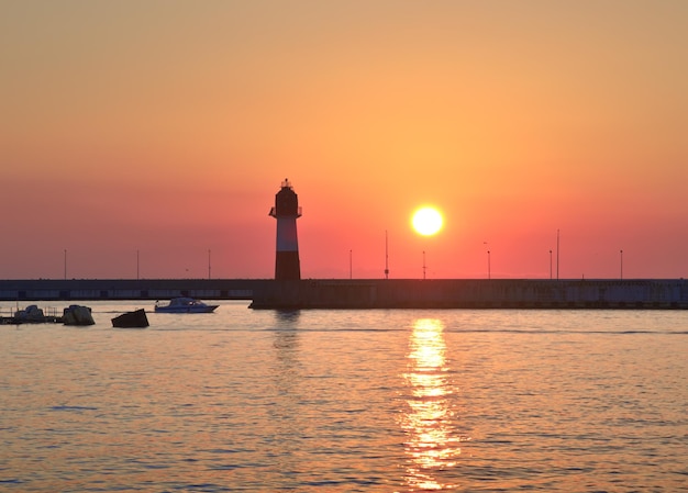 Puesta de sol en el faro de Sochi, zona de aguas de la tarde en la estación marítima en la costa del Mar Negro