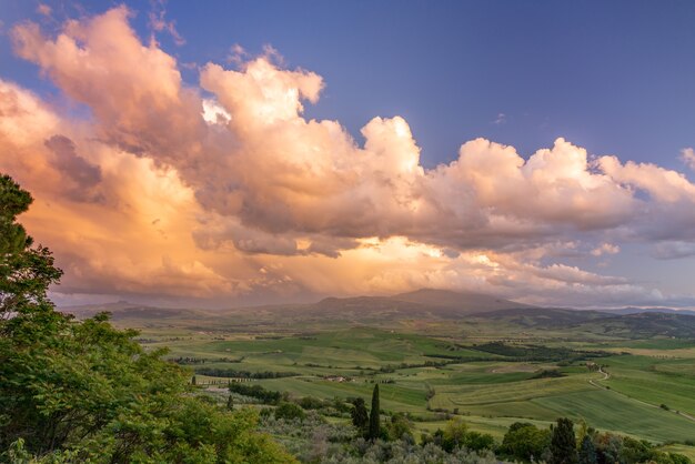 Foto puesta de sol iluminando nubes sobre tierras de cultivo cerca de pienza en toscana