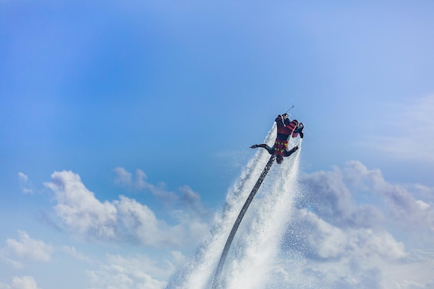 puesta de sol de la isla. Piloto profesional de flyboard haciendo voltereta hacia atrás con el fondo de una isla tropical