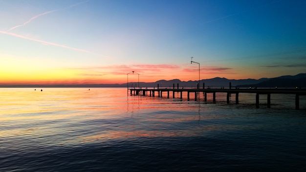 Puesta de sol en el lago de Garda, Italia. Paisaje italiano. Muelle en perspectiva