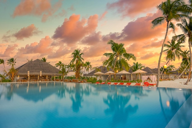 Puesta de sol de lujo sobre la piscina infinita en un complejo hotelero de verano frente a la playa en un paisaje tropical. Tranquilo