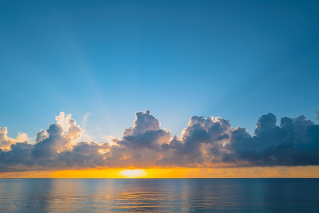 Puesta de sol en el mar con cielo y sol a través de las nubes sobre el océano y el cielo marino de fondo