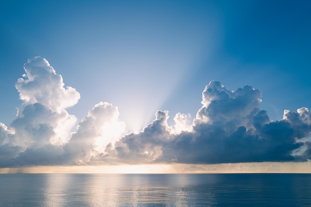 Puesta de sol en el mar con cielo y sol a través de las nubes sobre el océano y el paisaje marino de fondo del cielo