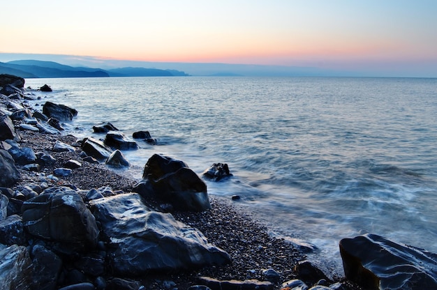 Puesta de sol en el mar negro Hermosas nubes cielo azul sol en el horizonte Hermosas piedras en primer plano