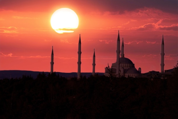 Foto una puesta de sol con una mezquita en primer plano y la puesta de sol detrás de ella.