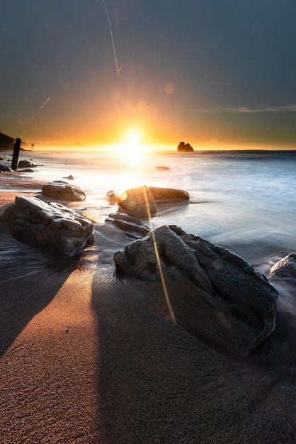 Foto puesta de sol mientras las olas del mar golpean las rocas en la playa de ilbarritz en biarritz, país vasco