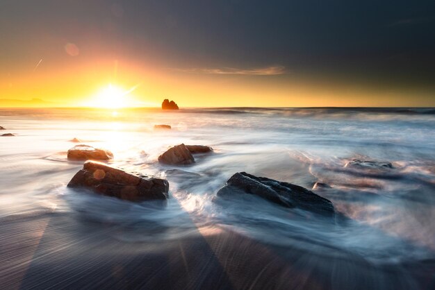 Puesta de sol mientras las olas del mar golpean las rocas en la playa de Ilbarritz en Biarritz, País Vasco