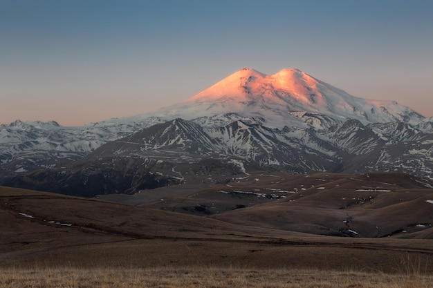 Puesta de sol montañas iluminadas por luz dorada Monte Elbrus cubierto de nieve Cáucaso Rusia