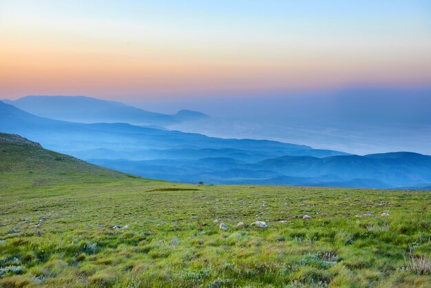 Puesta de sol en las montañas con rocas y pasto verde