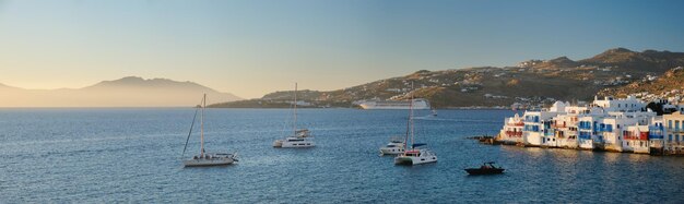 Foto la puesta de sol en mykonos, grecia, con cruceros y yates en el puerto