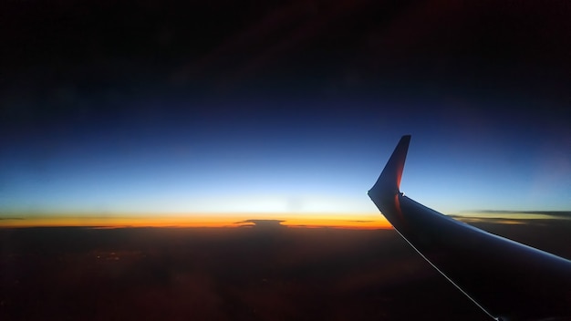 Puesta de sol naranja azul desde la altura del cielo. Ala de avión.