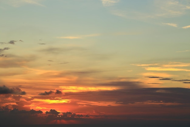 Puesta de sol naranja detrás de las nubes y el cielo azul