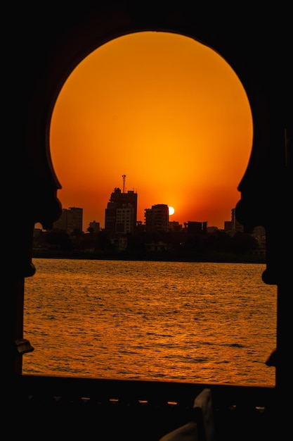 Puesta de sol naranja en el río Nilo desde un barco el sol se esconde en los edificios