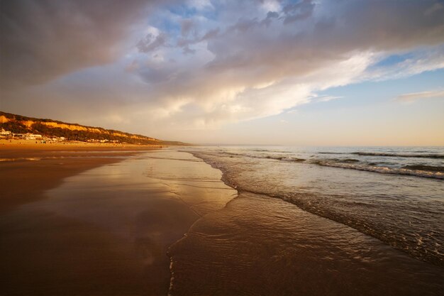 Puesta de sol en el océano Atlántico con olas en la playa Fonte da Telha Costa da Caparica Portugal