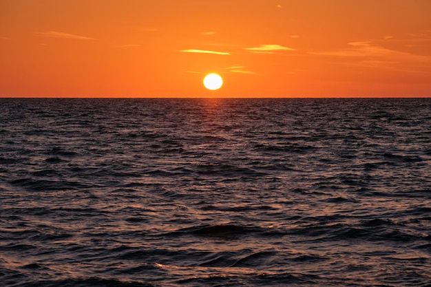 Puesta de sol en el océano Gran sol blanco sobre fondo de cielo brillante espectacular Nube de noche suave sobre el agua oscura del mar