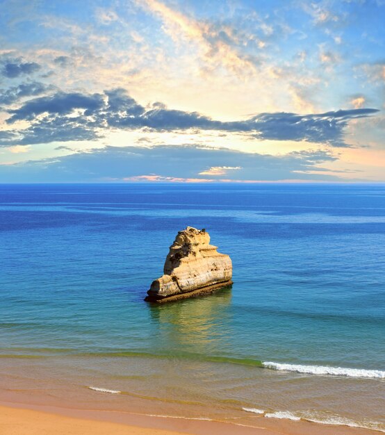 Puesta de sol en la playa de arena Praia dos Tres Castelos con formaciones rocosas, Portimao, Algarve, Portugal.