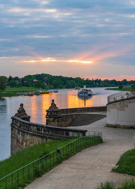 Foto la puesta de sol en el río elba en la famosa ciudad de dresde los barcos de recreo turísticos navegan lentamente a lo largo del río al atardecer más allá de una hermosa escalera en el parque