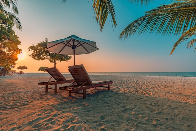 Puesta de sol romántica, tumbonas de pareja, hojas de palma idílico fondo de paisaje de vacaciones de playa tropical