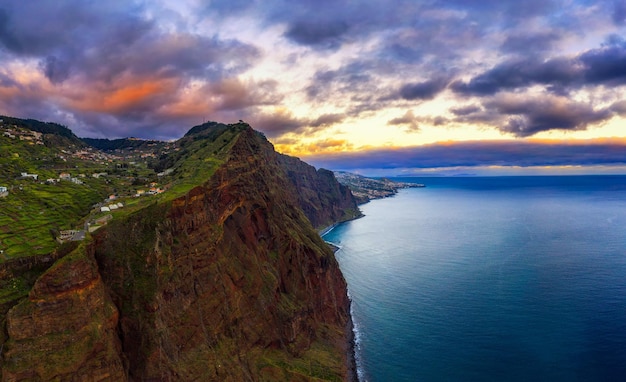 Puesta de sol sobre los acantilados de la isla de Madeira con la ciudad de Funchal al fondo