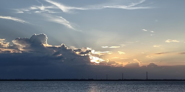 Una puesta de sol sobre el agua del río con nubes dinámicas cielo azul y árbol