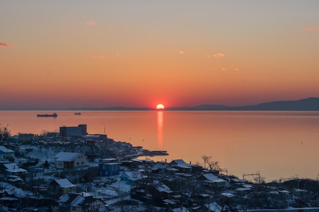 La puesta de sol sobre la ciudad que se encuentra en la orilla del mar