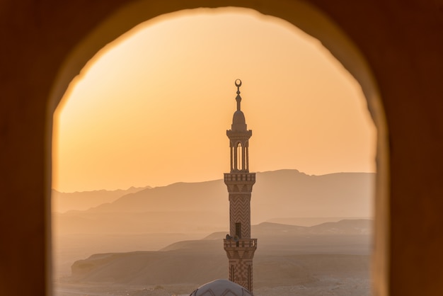 Puesta de sol sobre el desierto con la mezquita musulmana en primer plano