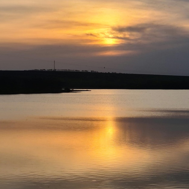 Una puesta de sol sobre un lago con un cielo nublado y algunas nubes.