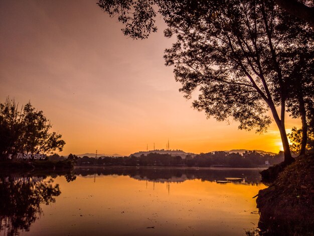 Una puesta de sol sobre un lago con un gran edificio al fondo