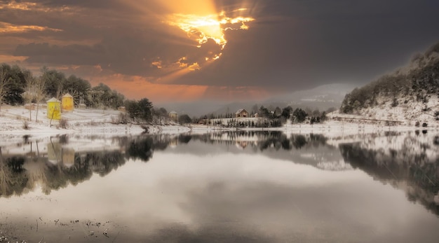 una puesta de sol sobre un lago con una montaña en el fondo