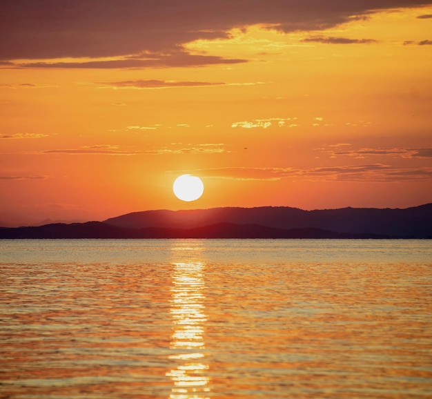 Puesta de sol sobre el mar Egeo Grecia Reflejo dorado sobre el agua del océano ondulado Tierra oscura y cielo colorido