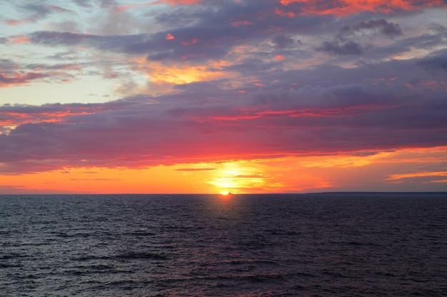 Puesta de sol sobre el mar: paisaje marino escénico al atardecer con horizonte marino y nubes de colores