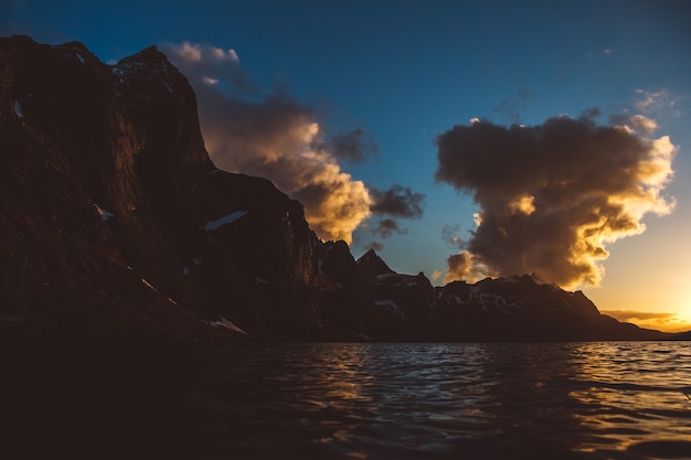 Puesta de sol sobre las montañas junto al mar. Silueta de las montañas. Hermosas nubes.