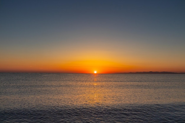 Puesta de sol sobre el océano con montañas al fondo