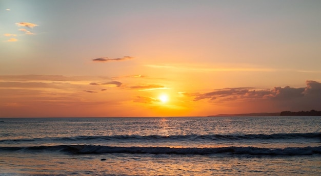 Una puesta de sol sobre el océano con una ola en el agua.