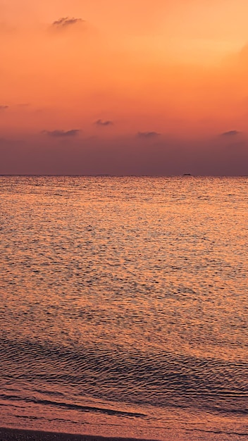 Una puesta de sol sobre el océano con una pareja en la playa