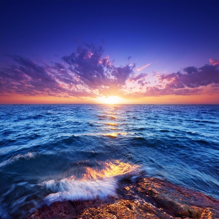 Una puesta de sol sobre el océano con una puesta de sol en el fondo