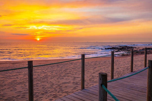 Puesta de sol sobre el océano Terraza de madera en la playa de arena al atardecer Hermosa costa en la noche Porto Portugal Europa