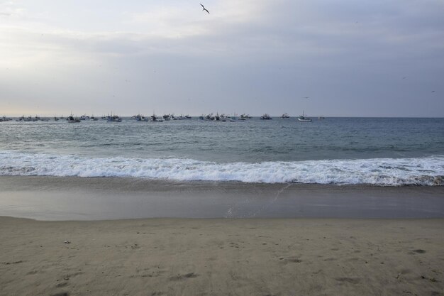 Puesta de sol sobre la playa de mancora con barcos de pescadores perú