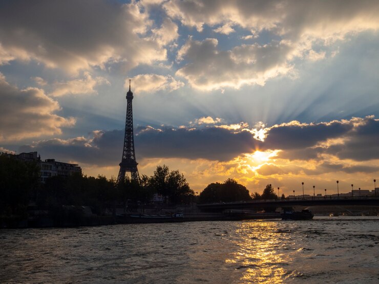 Foto puesta de sol sobre el río sena en parís, con vistas a la torre eiffel.