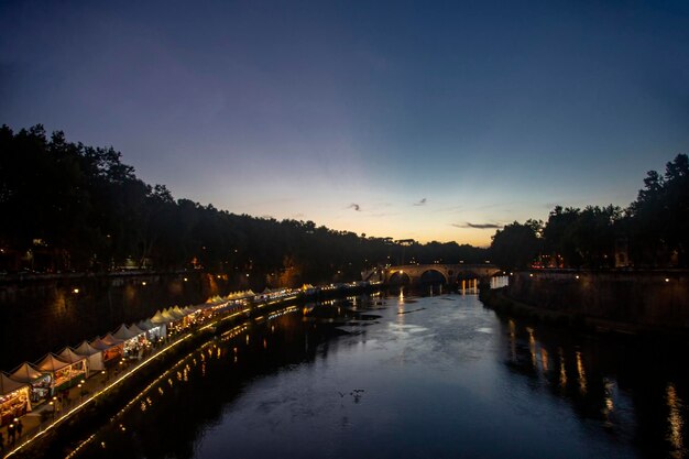 Puesta de sol sobre el río Tíber descanso nocturno en un café junto al río en Roma Italia