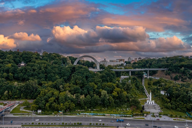 Puesta de sol sobre el verano de kiev con arco de amistad de los pueblos