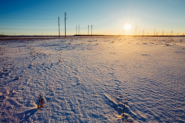 Puesta de sol sol en el horizonte de un campo cubierto de nieve