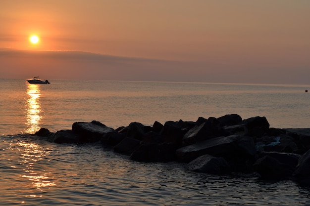 Puesta de sol de verano sobre el mar Barco y piedras