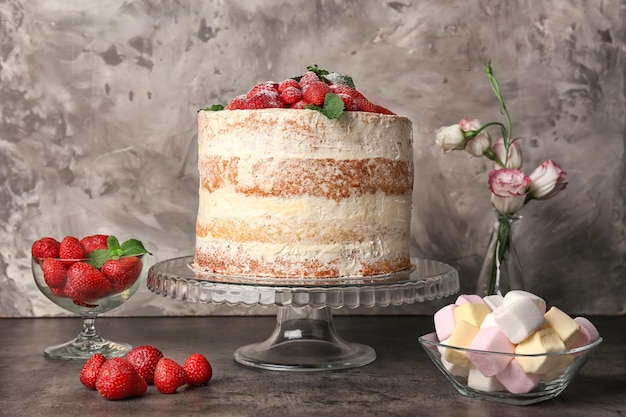 Puesto de pasteles con delicioso pastel de fresas en la mesa